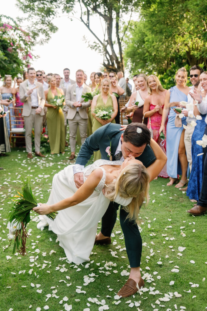 Bride and groom sharing a joyful dip kiss after the ceremony at their Bali destination wedding