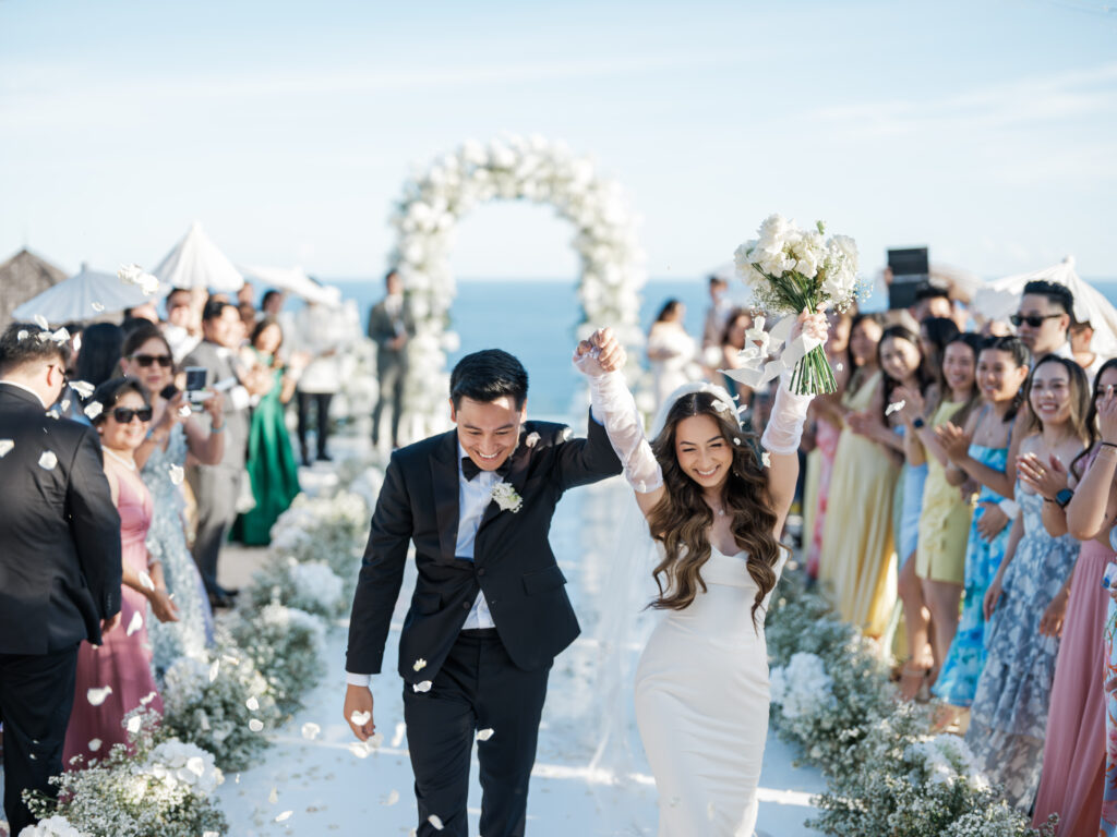 Oceanfront wedding ceremony in Uluwatu Bali with bride and groom celebrating down the aisle, showcasing a luxury cliffside wedding venue.