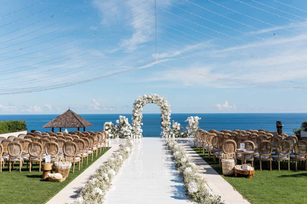 best uluwatu wedding venues bali cliff ceremony setup white aisle floral arch ocean view