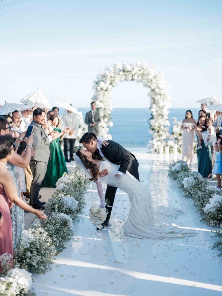 best uluwatu wedding venues bali ceremony couple kiss aisle floral arch ocean view guests