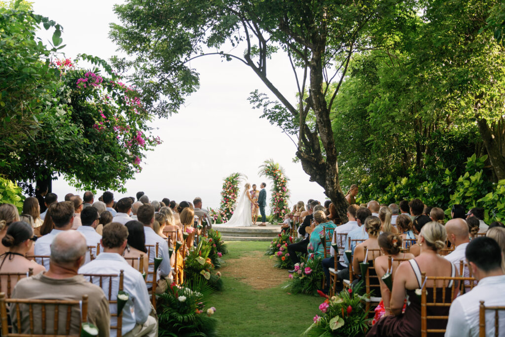 Elegant Bali wedding ceremony at Wonderland Uluwatu featuring a romantic garden setup, aisle seating, and breathtaking cliffside atmosphere.