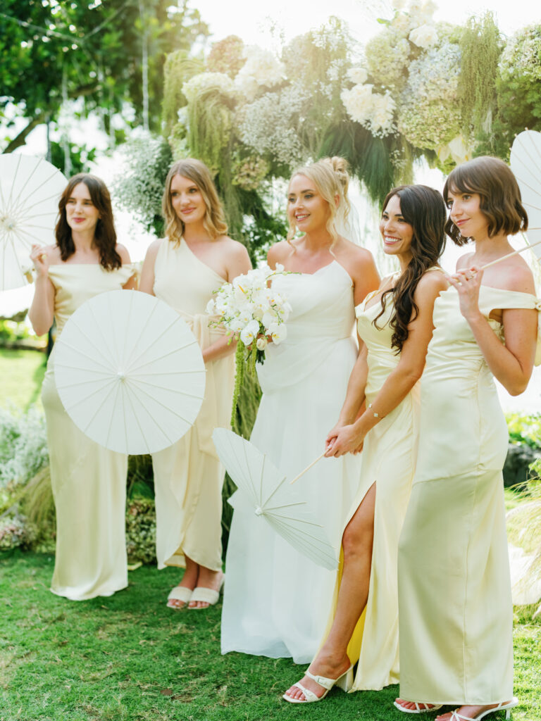 Villa Pemutih wedding Bali bridesmaids portrait with bride holding bouquet and floral arch backdrop in Uluwatu