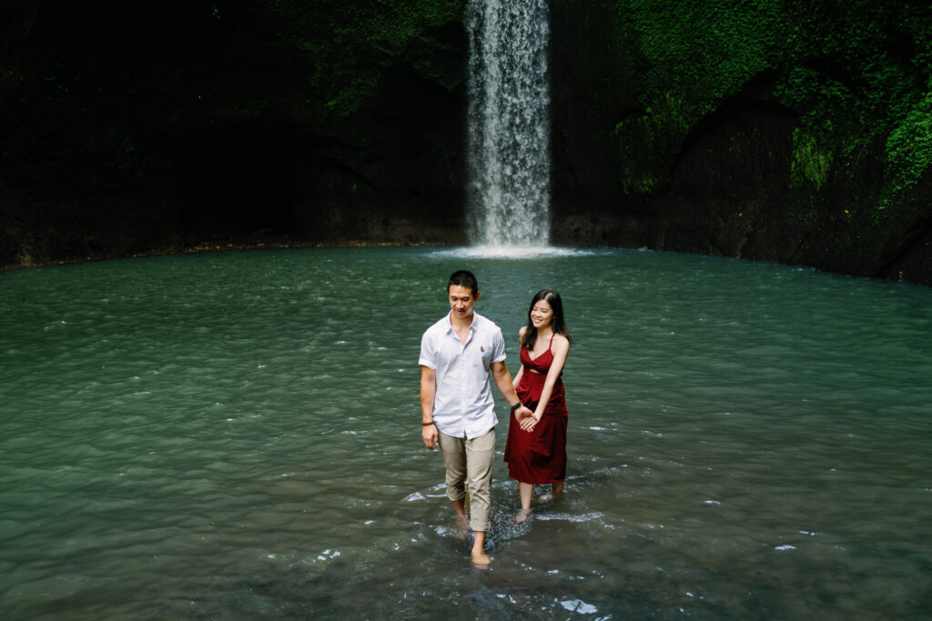 bali couple photoshoot tibumana waterfall couple walking in water ubud natural moment