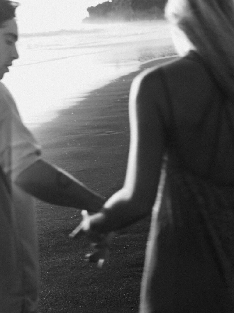 Bali couple session candid moment black sand beach holding hands