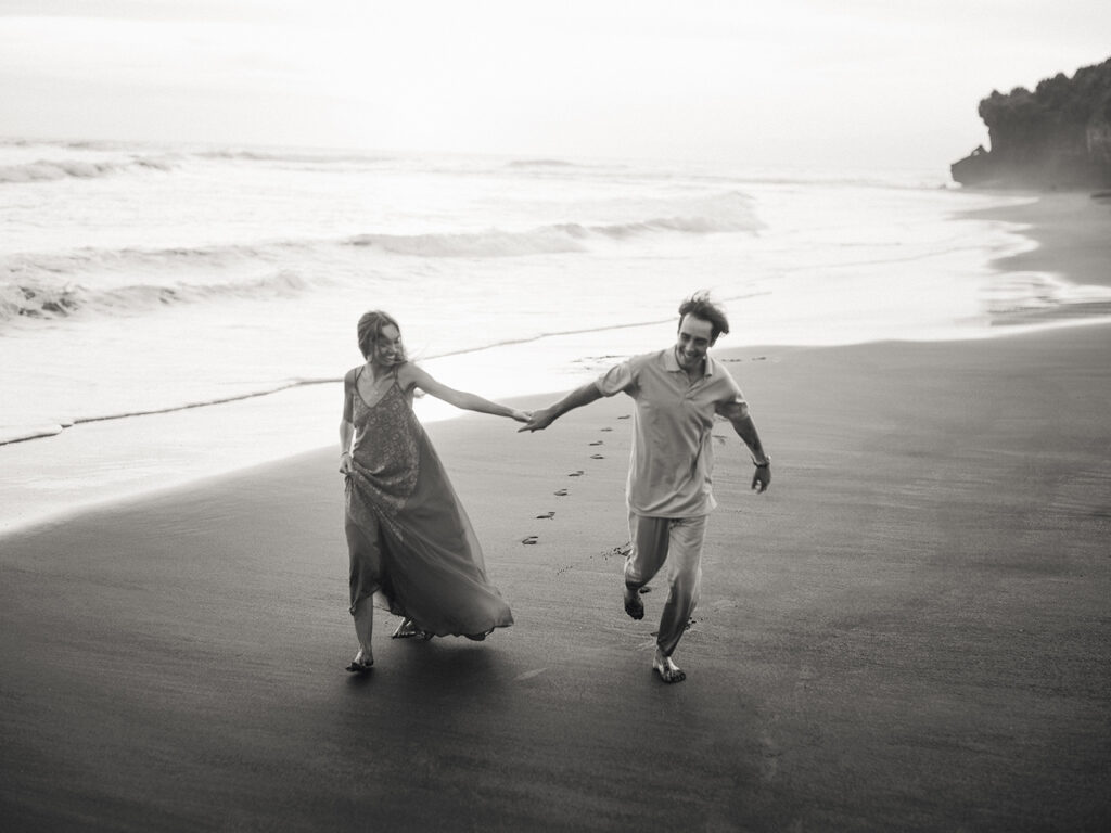 Pre-wedding photoshoot Bali candid couple running beach black white