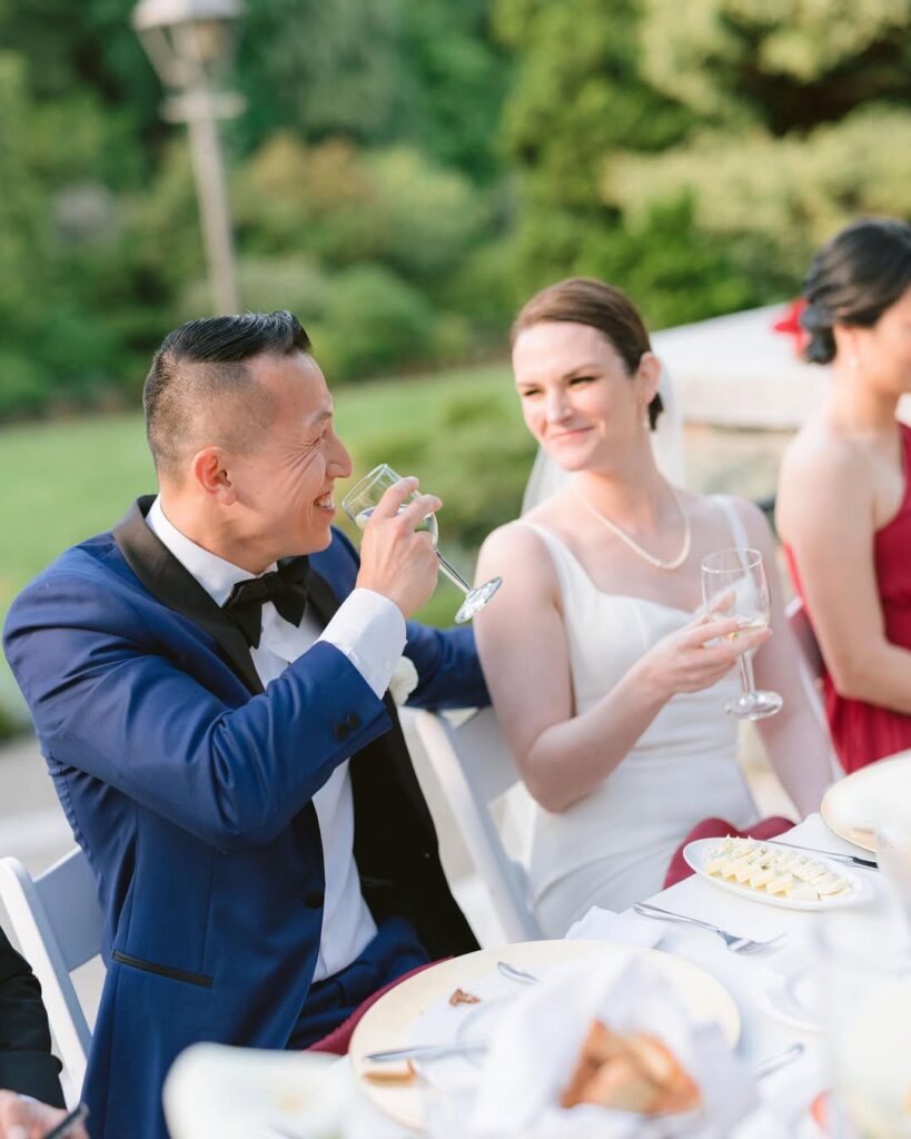 Tony laughing while toasting at Cecil Green Park House wedding reception, Amanda smiling beside him