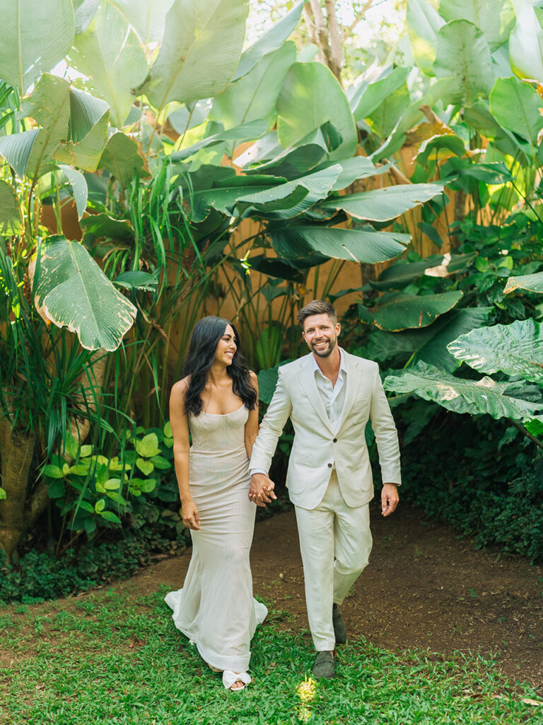 Bride and groom walking through tropical garden at Wonderland Uluwatu during an intimate sunset wedding Bali