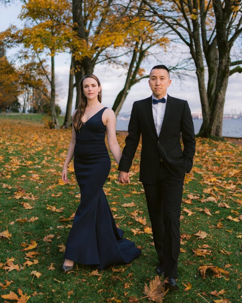 Amanda and Tony walking toward camera through fallen autumn leaves at Stanley Park, Vancouver waterfront