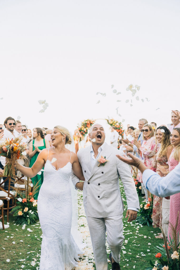 Aimee and Blake walking down the aisle during their Bali wedding experience as guests celebrate and throw petals