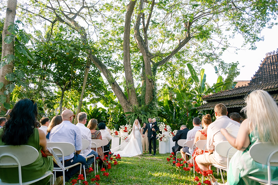 intimate villa wedding ceremony in Bali with couple walking down the aisle surrounded by guests