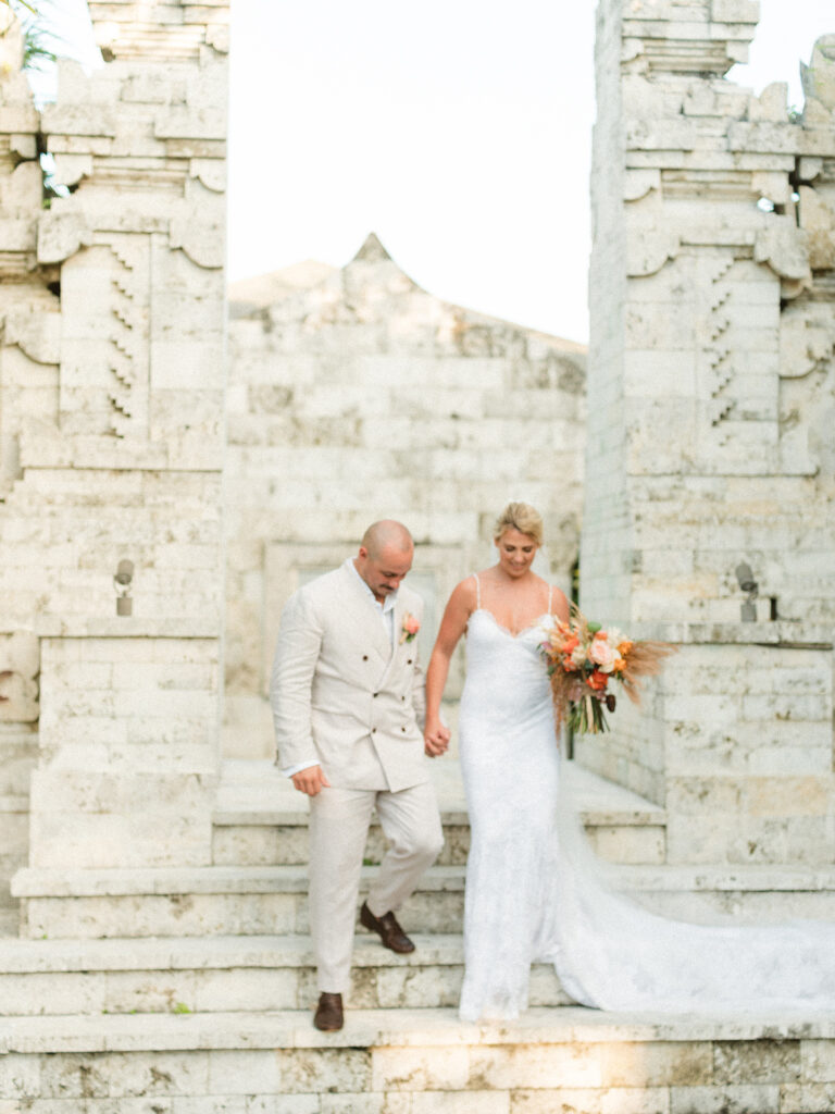 Aimee and Blake walking down stone steps during their Bali wedding experience, holding hands in a natural candid moment