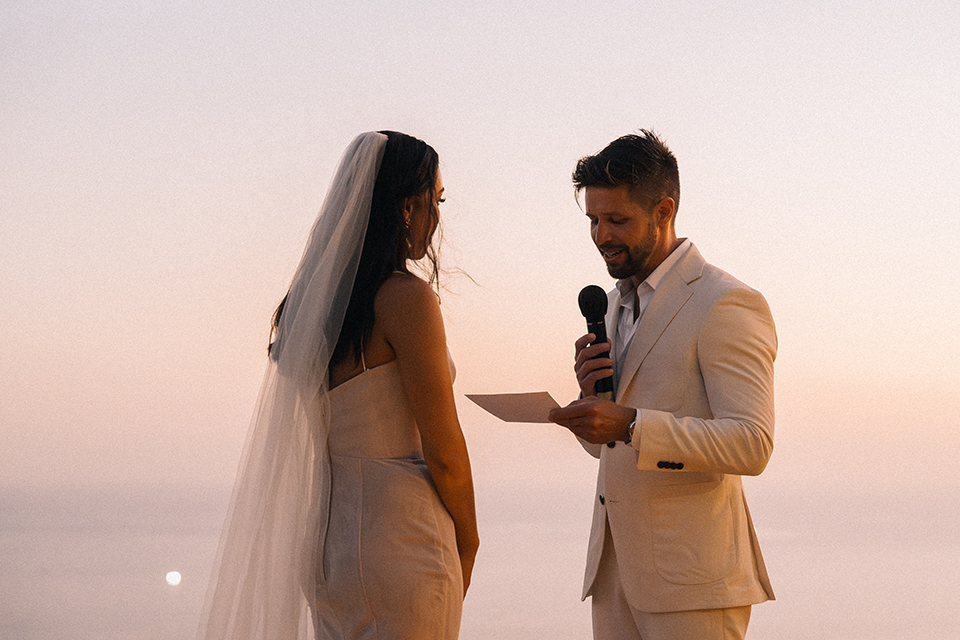 Intimate sunset wedding Wonderland Uluwatu with bride and groom standing on a candlelit stage overlooking the ocean at dusk