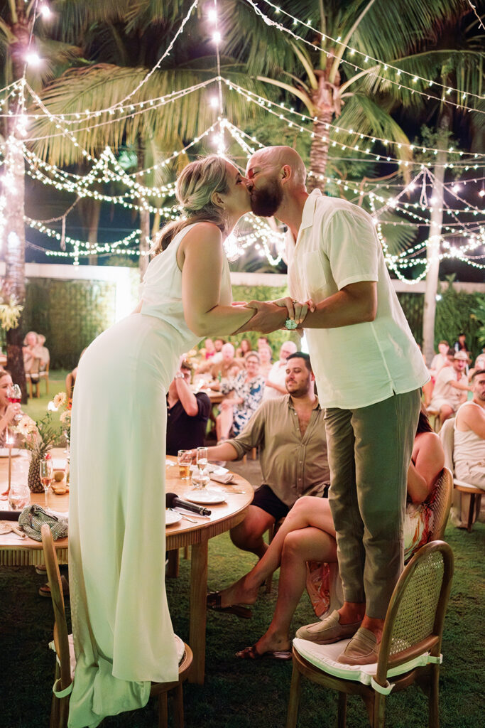 intimate elegant wedding in Bali couple kissing during reception dinner at Villa Vedas under string lights and tropical garden setting