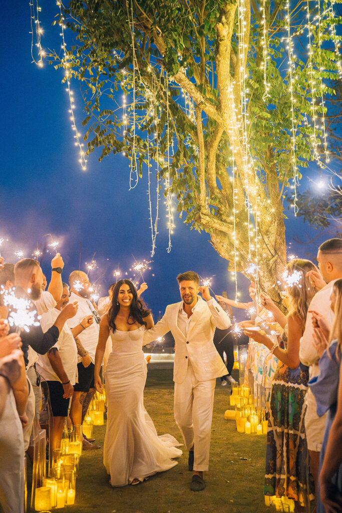 Bride and groom walking through guests with sparklers at intimate wedding reception in Wonderland Uluwatu at night