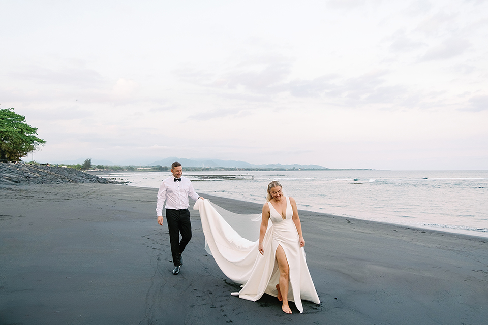 intimate villa wedding in Bali couple walking on beach with bride dress flowing