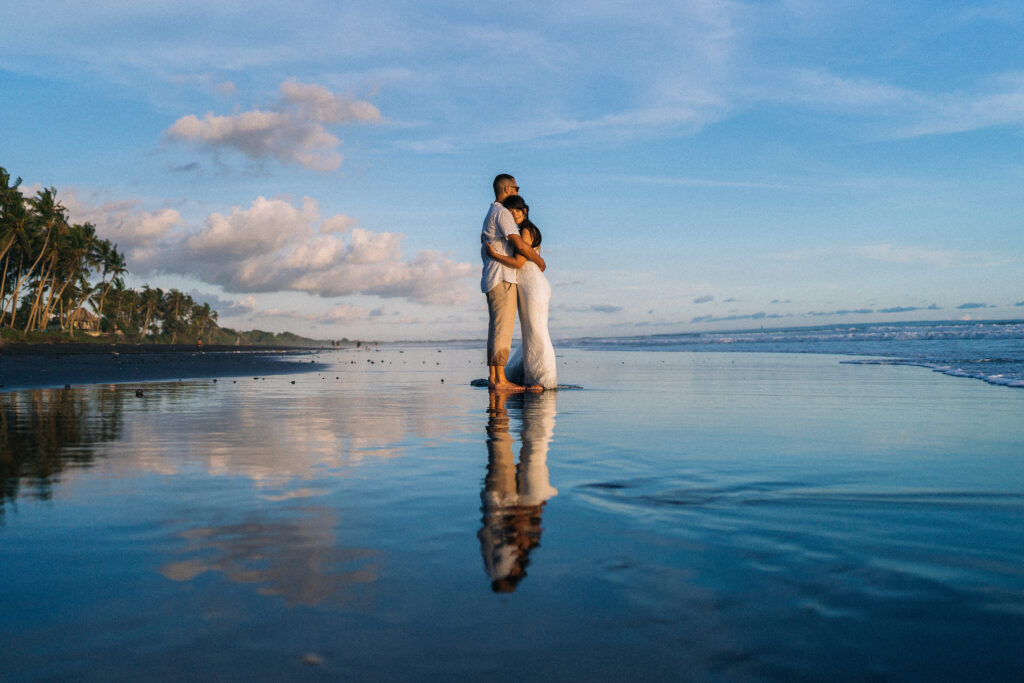 Bali couple photoshoot black sand beach golden hour reflection water