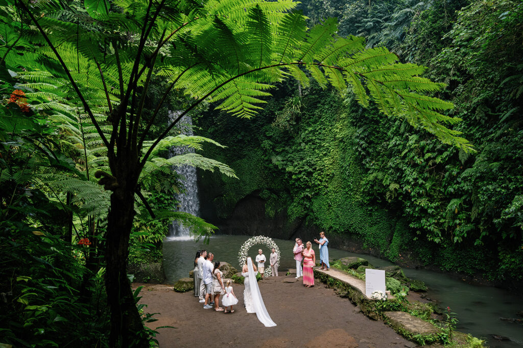 Bride walking down the aisle at Tibumana Waterfall elopement in Bali surrounded by lush jungle