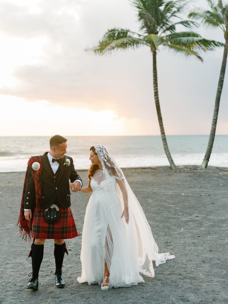 luxury multicultural wedding in Bali at Villa Vedas bride and groom walking on beach with Scottish tartan at sunset