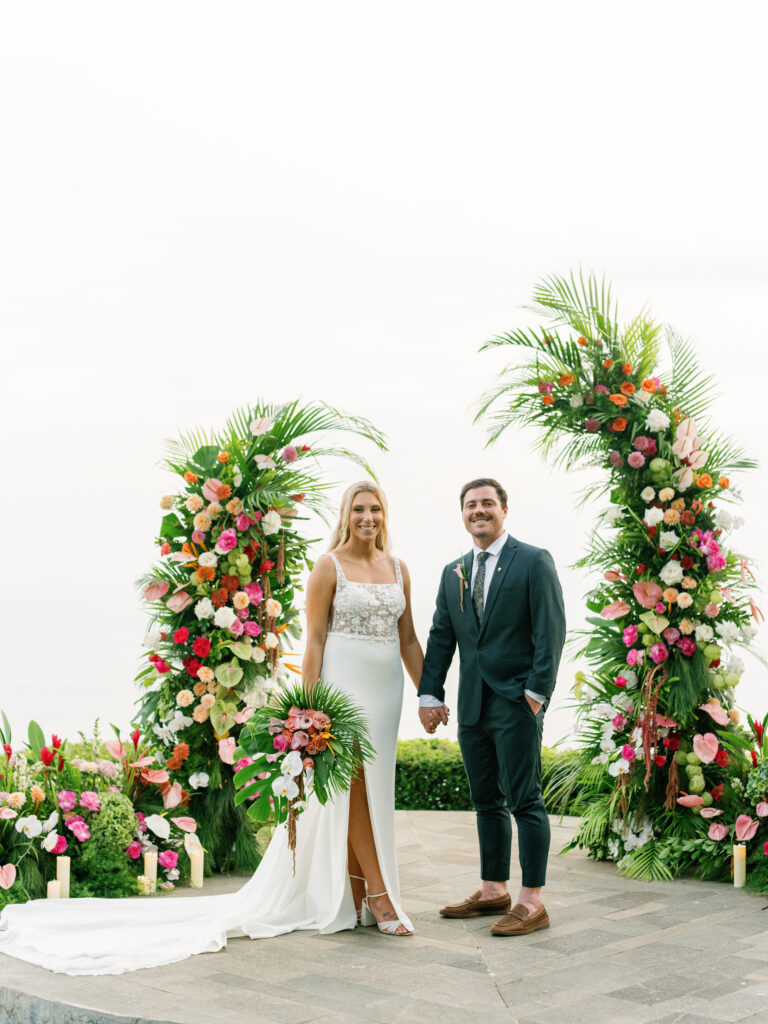 Wonderland Uluwatu wedding ceremony with bride and groom standing between floral arrangements on a Bali cliff