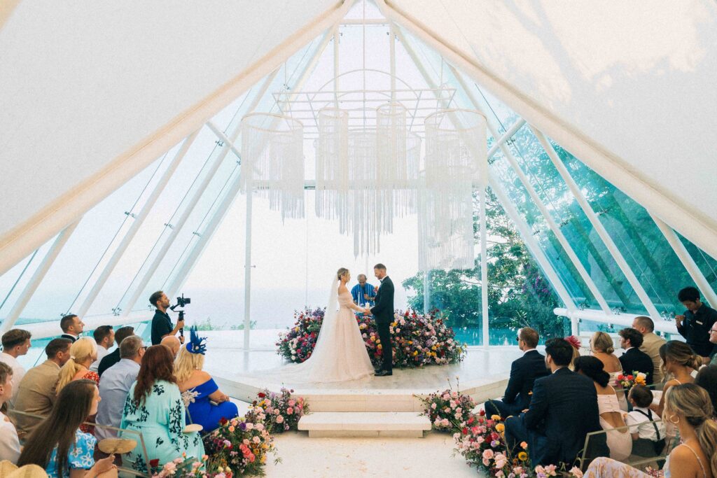 tirtha uluwatu wedding ceremony inside glass chapel bali couple exchanging vows ocean view