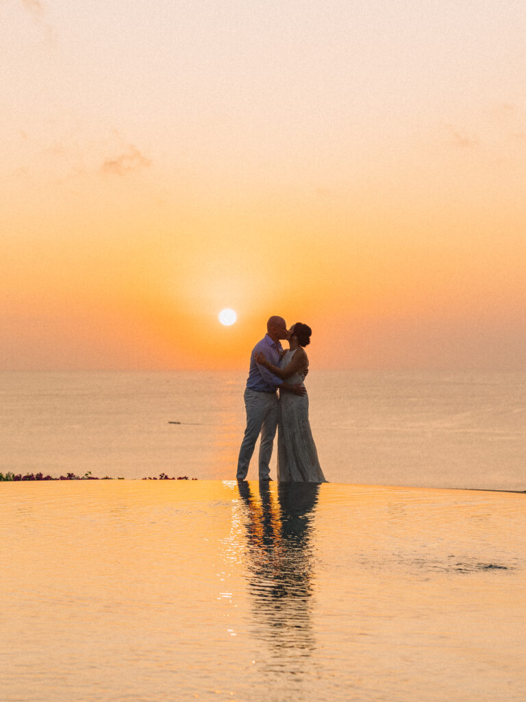 Bride and groom silhouette kissing at sunset in Uluwatu Bali with ocean view during a romantic golden hour wedding