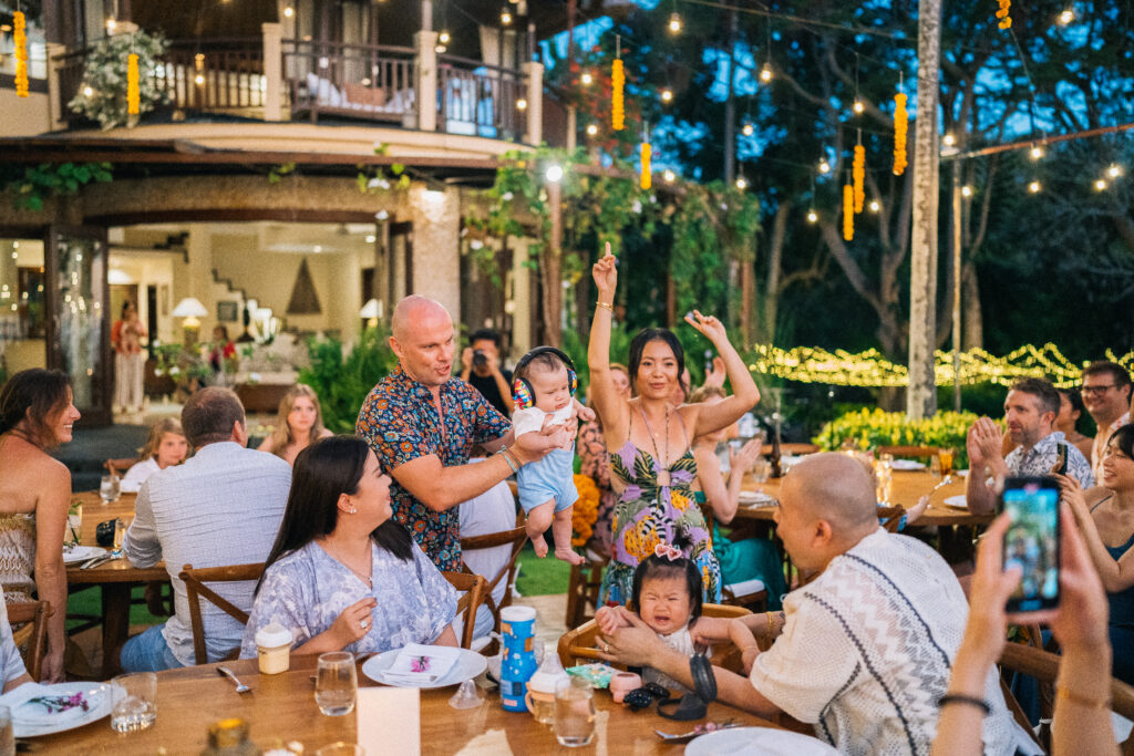 Wedding guests celebrating during an outdoor reception in Uluwatu Bali with warm evening lights and joyful atmosphere