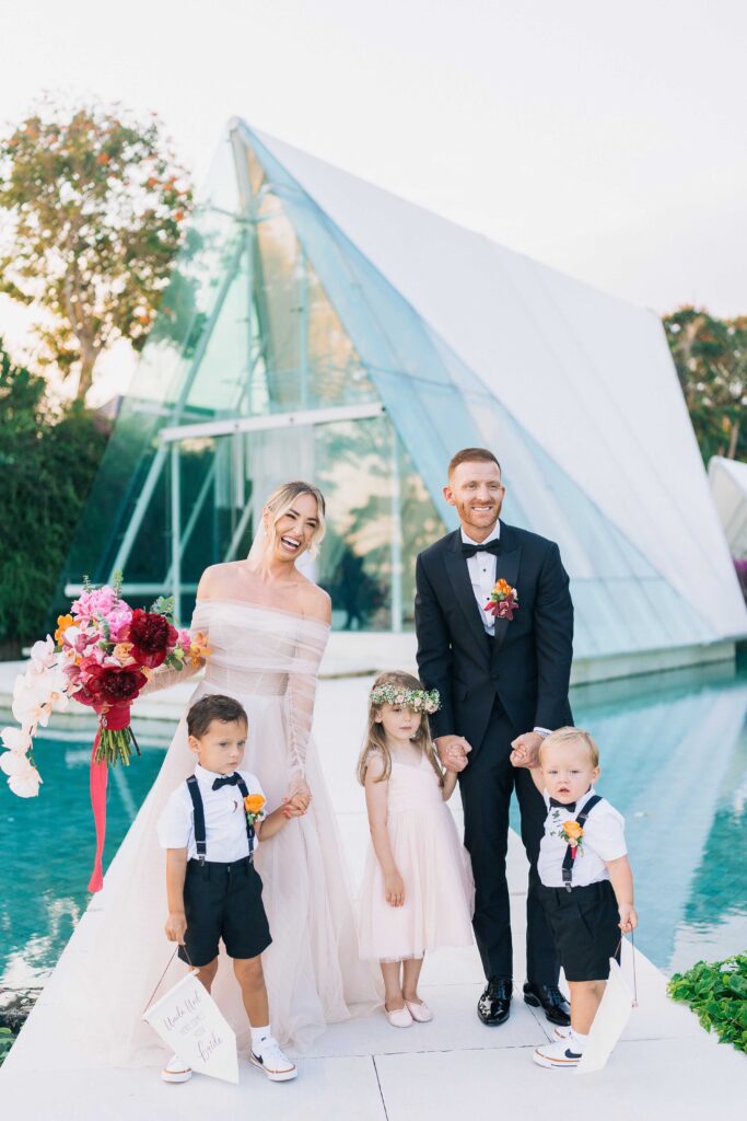 tirtha uluwatu wedding family portrait bali bride groom with children glass chapel background