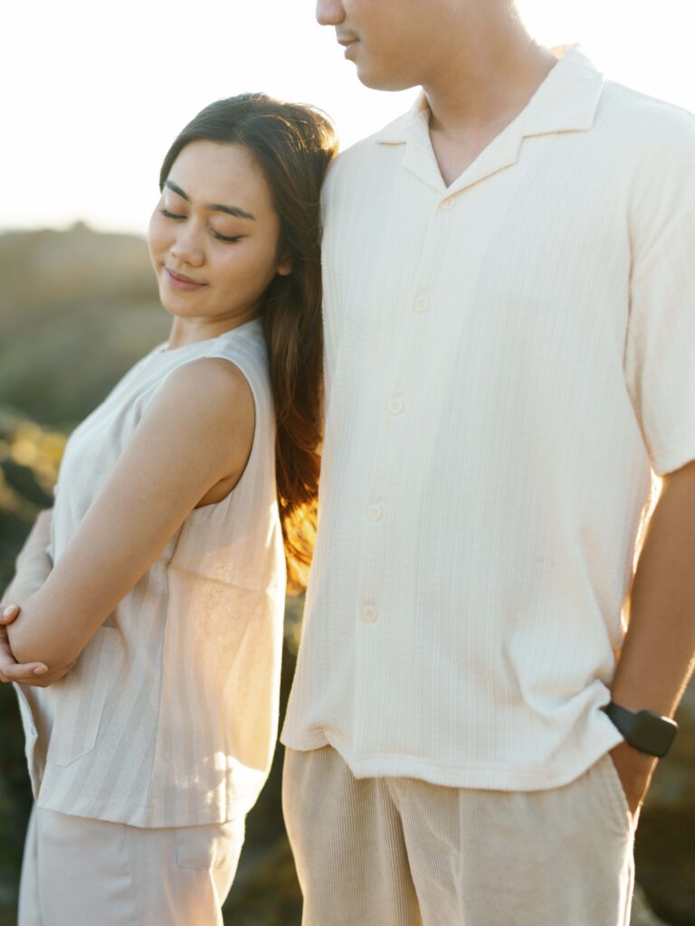 Honeymoon photoshoot Bali at golden hour featuring a couple standing close together with soft backlight, capturing a calm and intimate moment with natural expressions and warm tones.