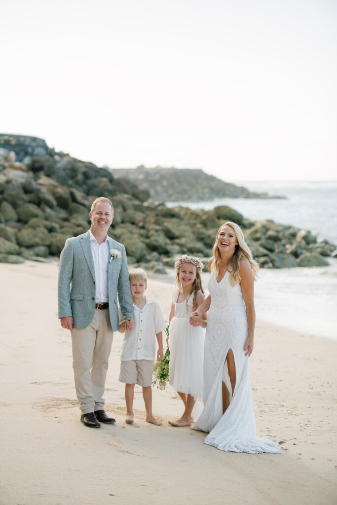 Family portrait at Melasti Beach Bali elopement — bride groom and children on white sand — Luxima Wedding
