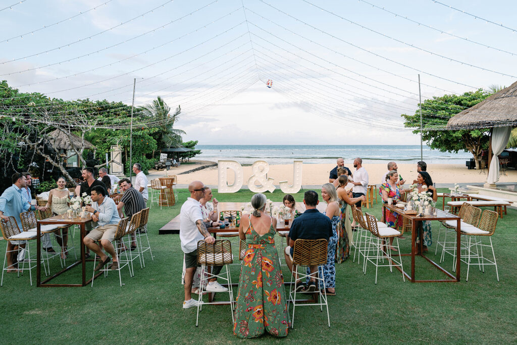 Beach Garden wide shot with D&J monogram Alt text: Wedding reception at Nusa Dua Beach Hotel Beach Garden Bali with D&J illuminated monogram and ocean view — Luxima Wedding photography