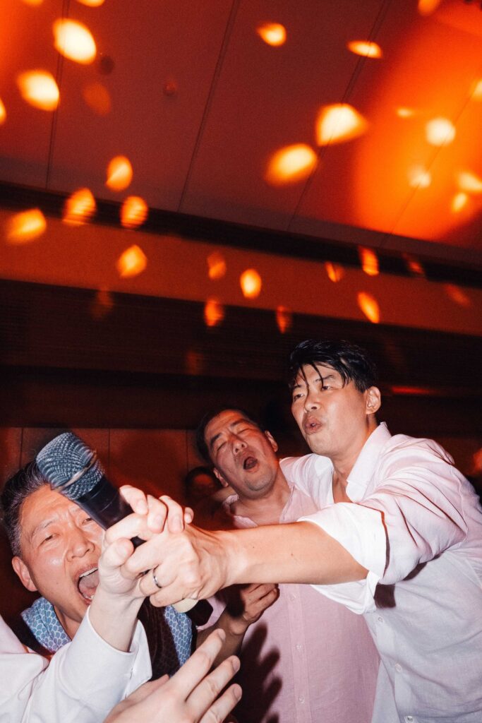 Wedding guests fighting over microphone at Padma Resort Ubud afterparty — candid karaoke chaos Bali wedding photography