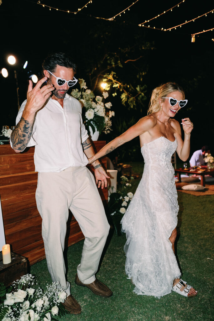 Reception — D&J sunglasses dancing Alt text: Bride and groom dancing in matching D&J heart sunglasses at Nusa Dua Beach Hotel wedding reception Bali — Luxima Wedding
