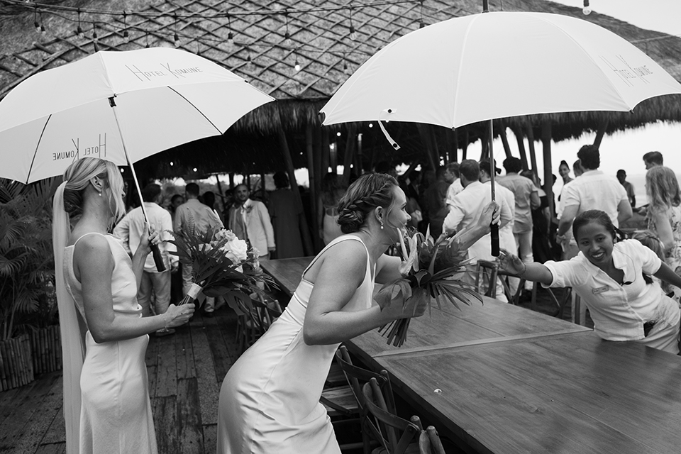 Komune Resort staff assisting bride with umbrella during rainy season wedding Bali