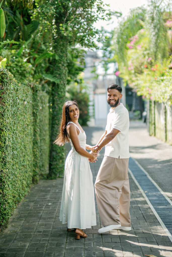 Newly engaged Indian couple holding hands on a tropical pathway in Canggu Bali after their surprise proposal