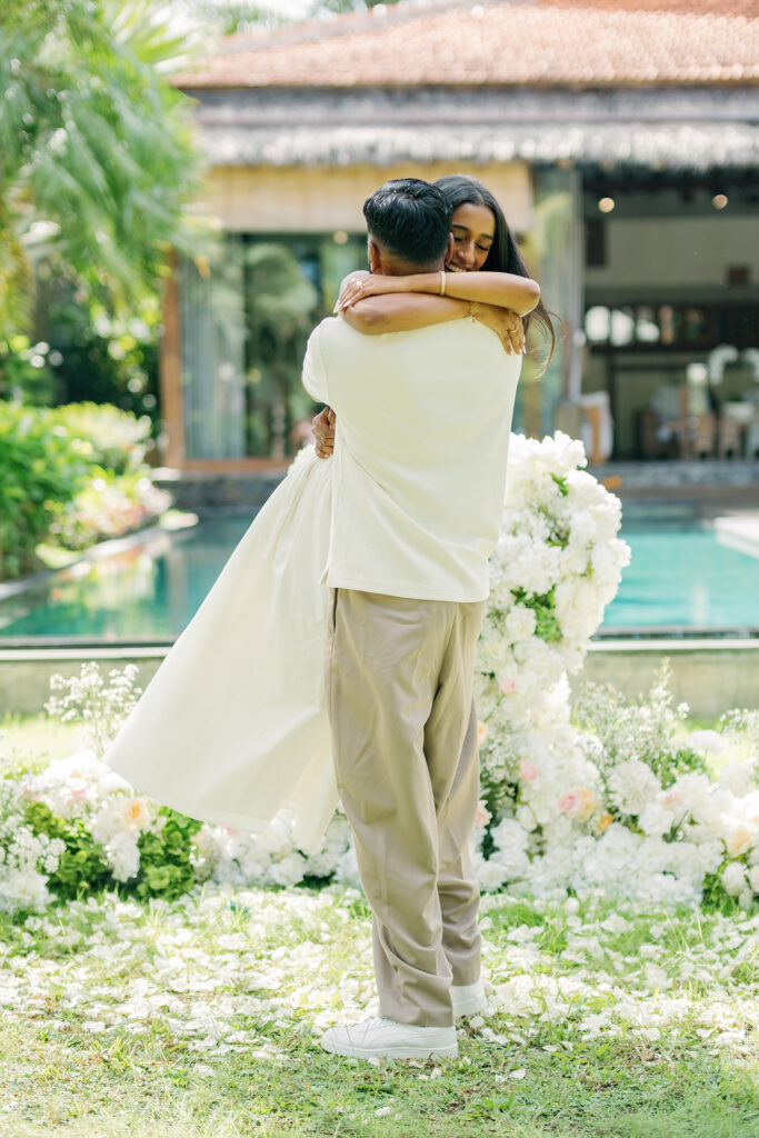 Newly engaged couple hugging in front of the floral proposal setup at Villa Desa Roro Bali