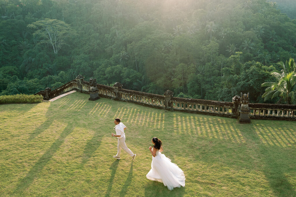 Aerial view of bride and groom running across lawn at Puri Wulandari Ubud Bali wedding — documentary photography by Luxima Wedding