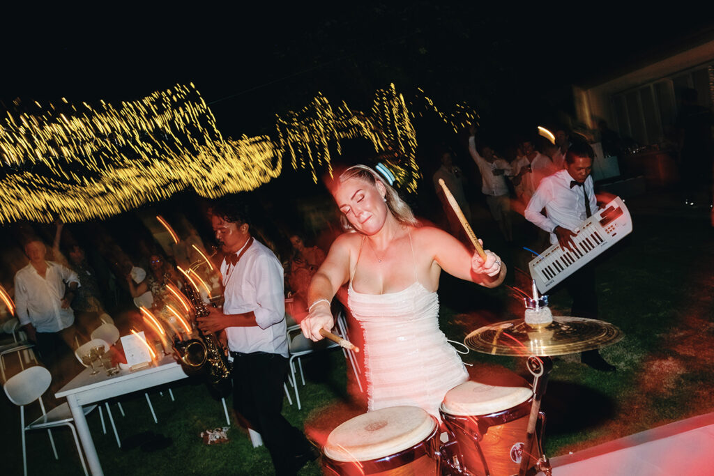 Bride playing drums on the dance floor at a lively Bali wedding reception