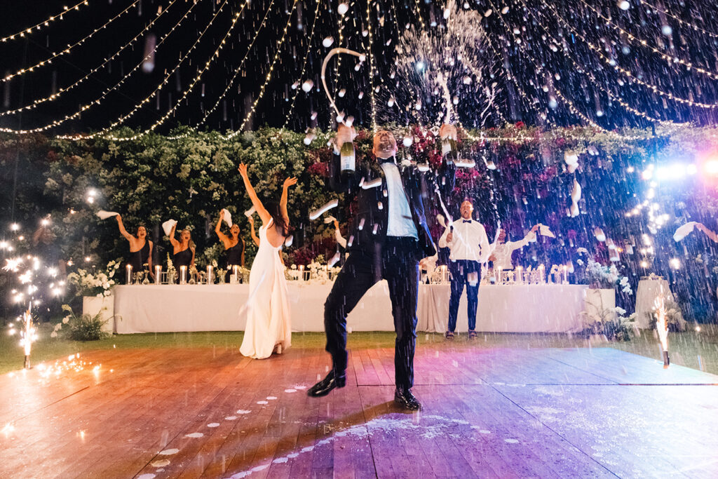 Groom popping champagne with sparklers on the dance floor at a Bali wedding reception