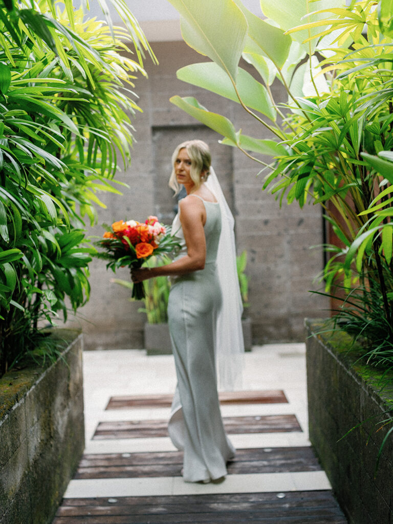 Alt: Bride and bridesmaids walking through bamboo corridor at Komune Resort Bali weddin