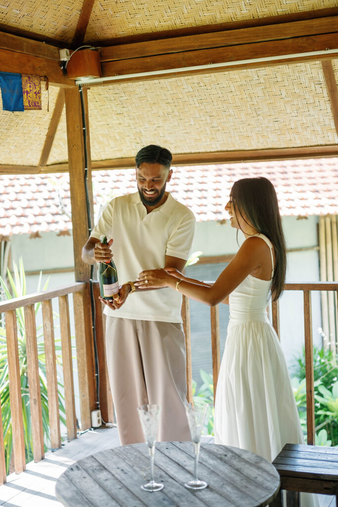 Couple celebrating their engagement with champagne on the villa balcony in Bali