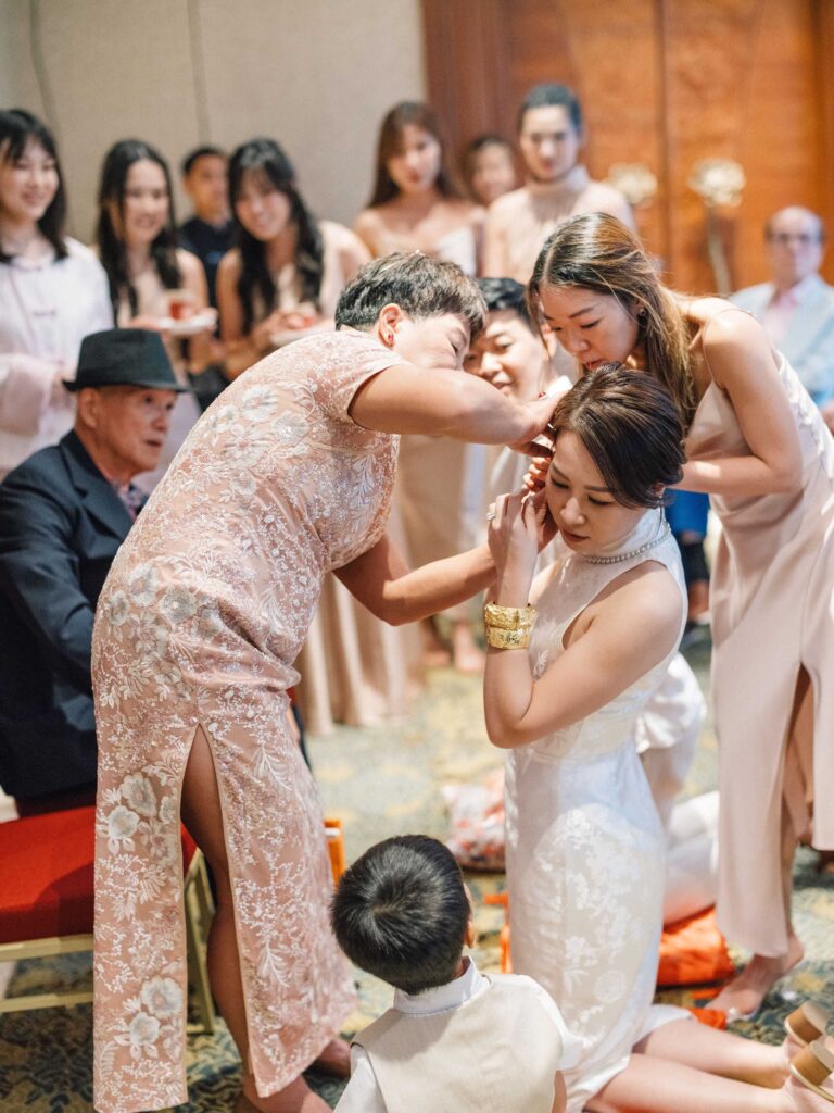 Mother placing gold earring on bride during Chinese tea ceremony at Padma Resort Ubud Bali — intimate family moment wedding photographer