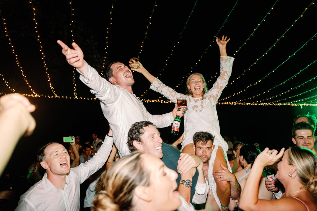 Wedding guests celebrating on the dance floor at a Bali reception under fairy lights