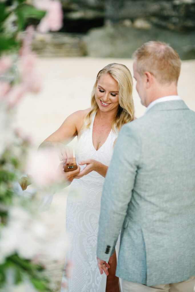 Bride opening ring box during early morning beach elopement ceremony at Melasti Bali