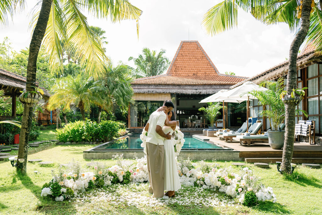 Couple sharing a quiet moment during a surprise proposal at Villa Desa Roro Canggu Bali surrounded by tropical garden and white floral decoration