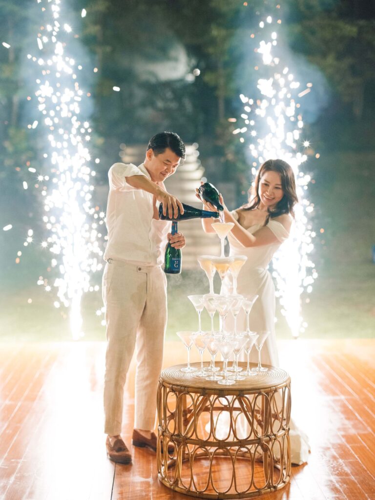 Terry and Jimmy pouring champagne tower with cold pyrotechnics at Padma Resort Ubud wedding reception — Bali wedding night photography