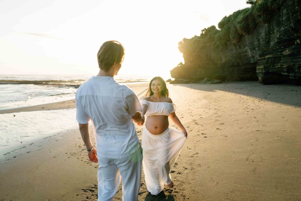 Elly walking hand in hand with Tom on Nyanyi Beach Bali maternity photoshoot