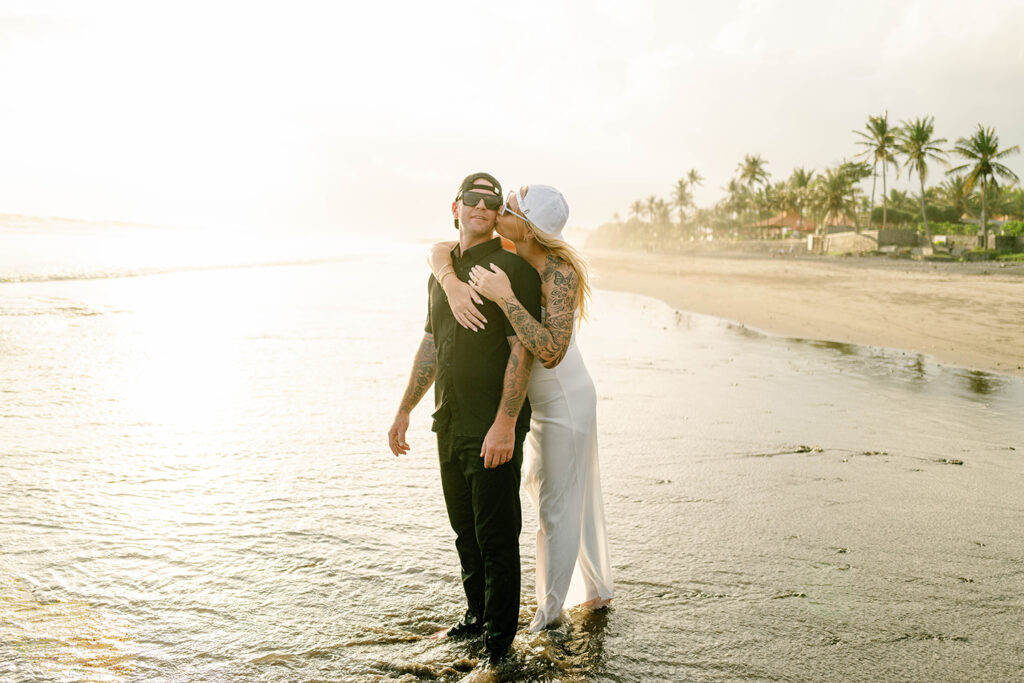 Kaytie kissing Jamie on the cheek at Pasut Beach during golden hour vow renewal Bali — Luxima Wedding
